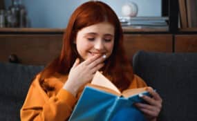 girl laughing while reading a book